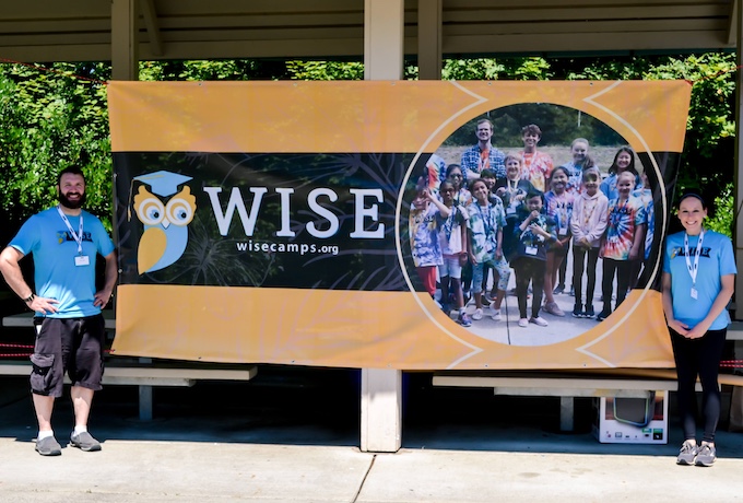 Bellevue Summer Camps - Wise Camps Executive Directors standing in front of the Wise Camps banner.